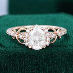 a ring with an oval cut diamond surrounded by smaller round diamonds on a green velvet surface