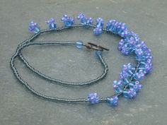 a blue and gray beaded necklace with an antique key hanging from it's end