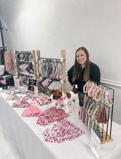 a woman standing next to a table with clothing on it and a dog in front