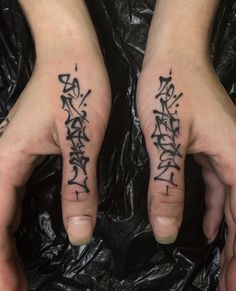 two hands with black writing on them and one has a finger tattoo in the middle