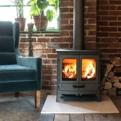 a wood burning stove in a living room next to a blue chair and potted plant