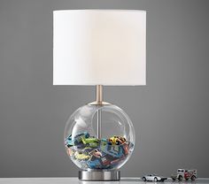 a lamp that is on top of a table with cars in the glass ball underneath it