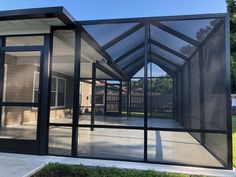 an enclosed patio area with glass walls and black trim on the sides, in front of a house