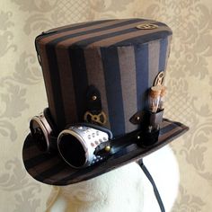 Steampunk all the way! This striking lady's top hat is covered with black and brown stripped fabric. It's main feature is a pair of metal silver toned goggles that sit at the center front...but that's only the beginning! Numerous gears are strategically placed here and there along with two long vials filled with watch parts and an antique bronze key at the back. The whole piece wouldn't be complete without a series of black leatherette straps and antique bronze studs pump up the steam! Measureme Top Hats For Women, Steampunk Top, Steampunk Top Hat, Watch Gears, Steampunk Hat, Bridal Hat, Mini Top Hat, Mini Top, Man Hat