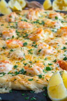 there is a pizza with shrimp and lemons on the table