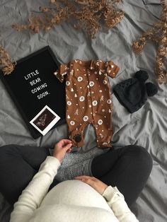 a baby laying on top of a bed next to a book and some other items