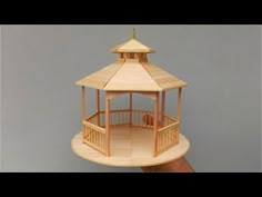 a wooden model of a gazebo in someone's hand on a gray background