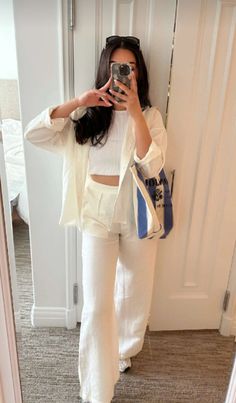 a woman is taking a selfie in the mirror while wearing white pants and a crop top