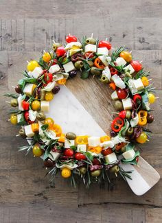 a wreath made out of olives, peppers and cheese on a wooden surface with a spatula