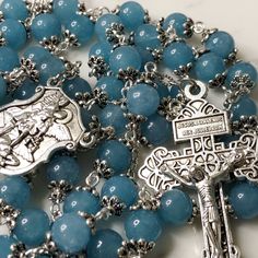 "Handmade traditional Catholic 5 decade rosary using large blue sponge quartz smooth round beads. Antique silver scalloped flower bead caps on every bead. Antique silver St. Michael the Archangel center with large Pardon Crucifix. All beads are 8mm. Designed to be used and/or displayed. Measures about 28\" long.  This rosary would make a beautiful gift for a baby shower, Baptism, First Communion, Reconciliation, Confirmation, or any other special event or occasion. Comes in a beautiful black velvet pouch.  I ship same or next business day.  All of my rosaries are one of a kind and are my own personal creation. Photos are a part of the description-you will receive the exact rosary pictured. Please don't hesitate to reach out if you have any questions! God Bless!" Blue Rosary With Round Beads For Healing, Blue Rosary With 8mm Beads For Healing, Blue Rosary For Healing, Blue Spiritual Rosary With Gemstone Beads, Spiritual Blue Rosary With Gemstone Beads, Blue Gemstone Beads Rosary For Spiritual Use, Blue Healing Rosary, St Michael The Archangel, Michael The Archangel