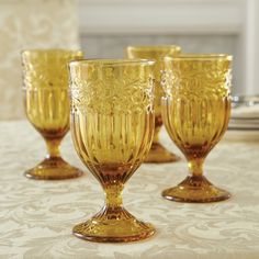 four yellow glass goblets sitting on top of a table