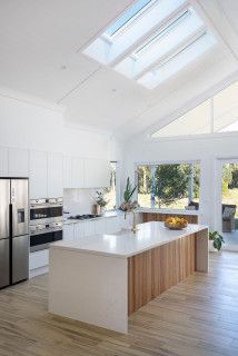 a large kitchen with an island in the center and skylights above it, is shown