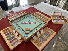 a monopoly board game set up on top of a red table with matching trays