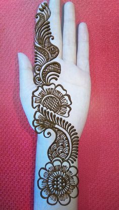 a hand with henna on it that is sitting on a pink surface and has an intricate