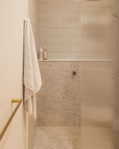 a white towel hanging on the side of a shower door