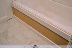 a bath tub sitting on top of a tiled floor next to a white door and wall