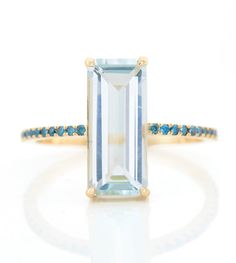 an emerald cut ring with blue sapphires on the sides and a diamond band around it