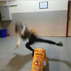 a man is falling off his skateboard in the middle of an empty room with a caution sign on the floor