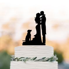 a wedding cake topper with a silhouette of a bride and groom standing next to their dog