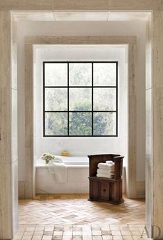 an open door leading to a bathroom with a bathtub and window in the background