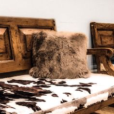 a brown and white pillow sitting on top of a wooden bench