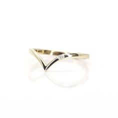 a yellow gold ring with white diamonds on the top and bottom, sitting on a white surface