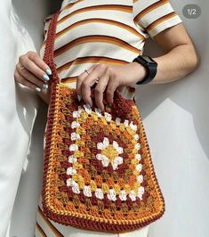 a woman is holding a crocheted purse