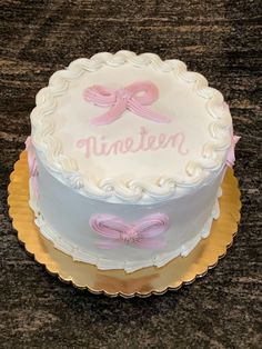 a white cake with pink ribbon and name written on the top is sitting on a table