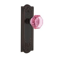 the pink glass door knob is attached to an antique style doorknobl with a decorative design