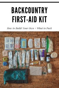 the backcountry first - aid kit is laid out on a wooden table