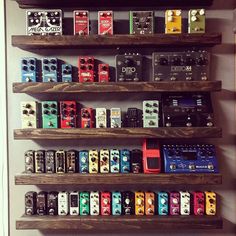 several different types of guitar pedals are arranged on wooden shelving in a room