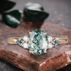 a green and white stone ring sitting on top of a wooden table next to leaves