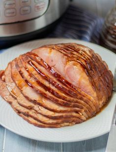 sliced ham on a white plate next to an instant pot roast honey ham in the pressure cooker