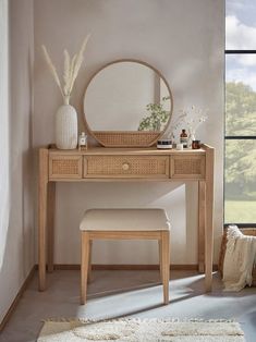 a wooden vanity table with a mirror and stool in front of a window next to a white rug