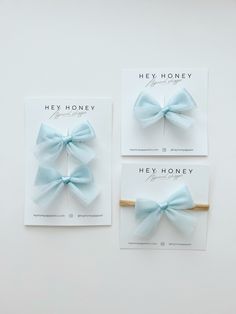 two cards with bows on them sitting next to each other in front of a white wall