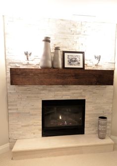 a fireplace with white brick and wooden mantel above it, surrounded by vases