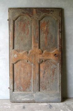 an old wooden door with carvings on the sides and two doors in different directions, against a white wall