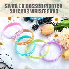 Our Embossed Printed Wristbands are similar to our Embossed Wristbands which are produced with raised text style but the difference is that they are additionally silk screen printed with ink. They exhibit an elevated graphical effect on the bands where the artworks or printed messages protrude out of the surface. The raised texts are printed with single or multiple colors through precise silk screen printing technology which vibrantly displays your customized message. To create a noticeable and attractive appearance, we recommend selecting contrasting colors for the bands and the ink. This is what makes these wristbands exceptional and out of the box promotional items for giveaways, advertising, and branding purposes. These 1/2 inch decorative wristbands are great promotional products for Silicone Bracelets, Promotional Items, Text Logo, Promotional Item, Text Style, Silk Screen Printing, Promotional Products, Wristbands, Silk Screen