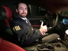 a man sitting in the driver's seat of a car giving a thumbs up