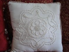 a white embroidered pillow sitting on top of a couch