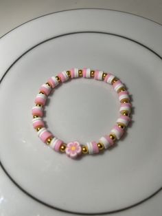 a pink and gold beaded bracelet sitting on top of a white plate