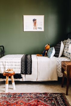 a bedroom with green walls and white bedding, wooden stools on the floor