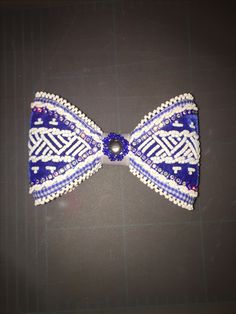 a blue and white beaded bow tie on top of a black surface with lines in the background