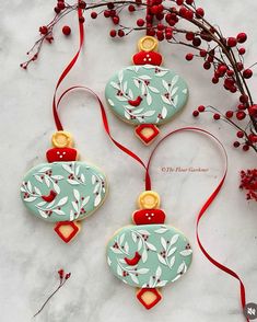 two ceramic ornaments with red ribbons and berries