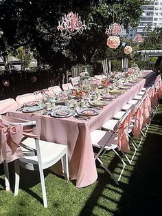 a long table is set up with pink linens