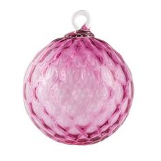 a pink glass ornament hanging from a string on a white background with clippings