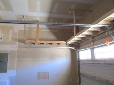 the inside of a garage with no doors or windows, and ladders hanging from the ceiling