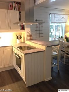 a kitchen with an oven, sink and dining room table in the backround