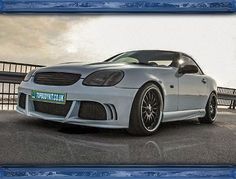 a silver sports car parked in front of a fence