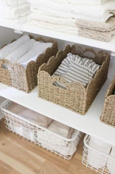 wicker baskets are stacked on top of white shelving in a closet with folded towels